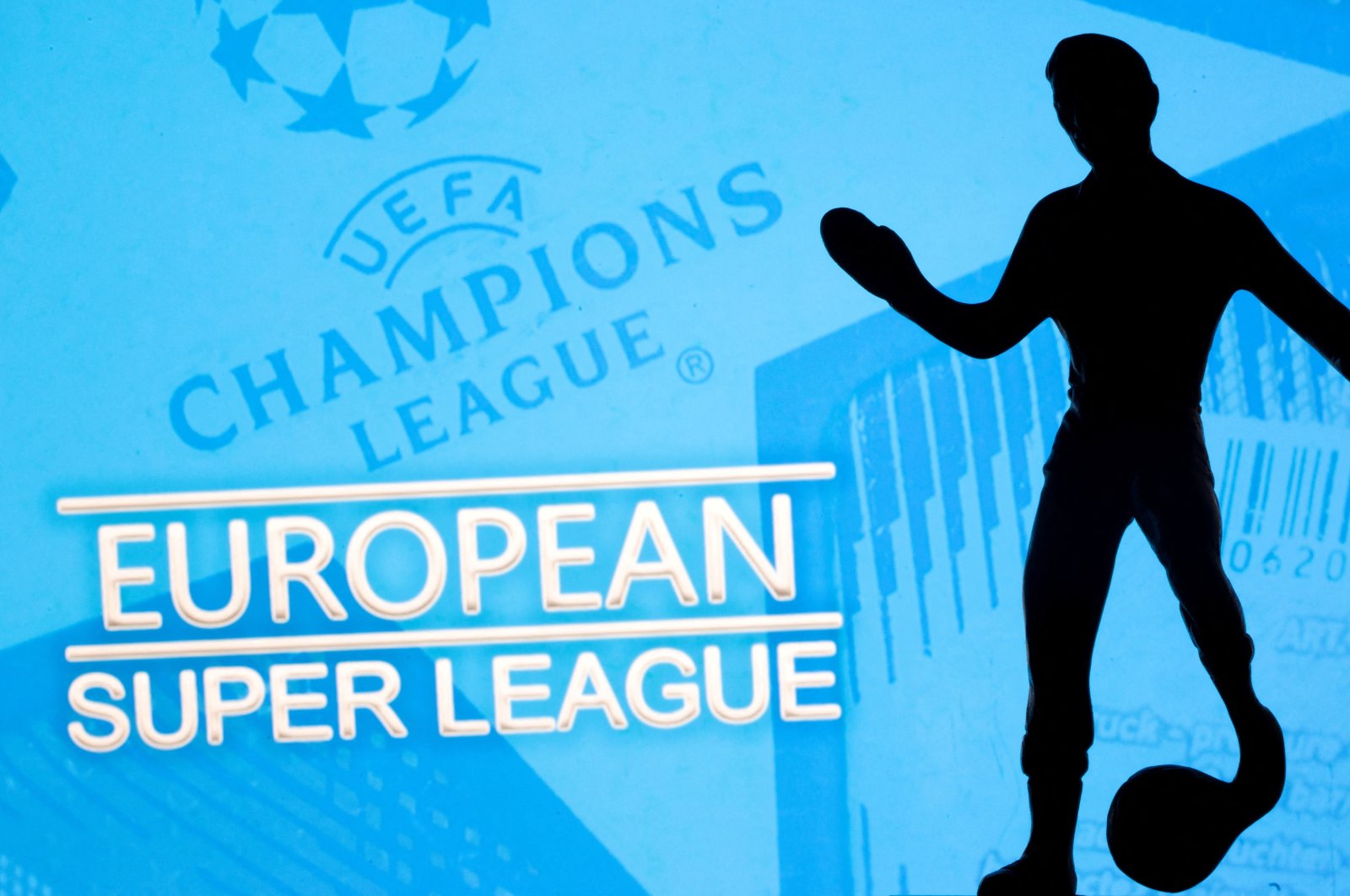 A metal figure of a football player with a ball is seen in front of the words &quot;European Super League&quot; and the UEFA Champions League logo in this illustration taken April 20, 2021. (Reuters File Photo)