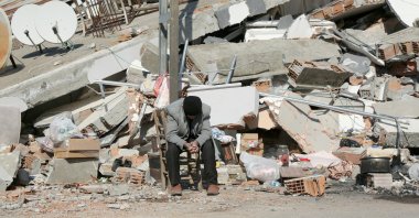 A man sits in front of a collapsed building following an earthquake in Adıyaman, southeastern Türkiye, Feb. 11, 2023. (Reuters Photo)