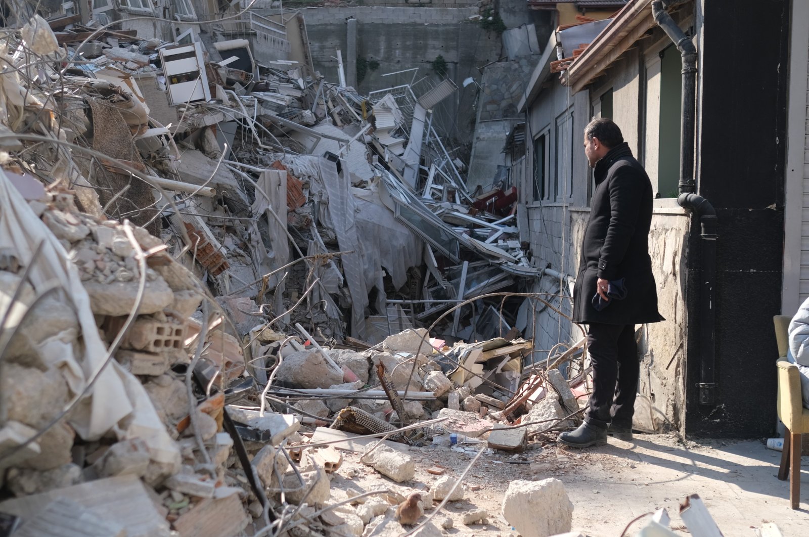 Idris Kan looks at the rubble he escaped from, in Hatay, southern Türkiye, Feb. 12, 2023. (IHA Photo)