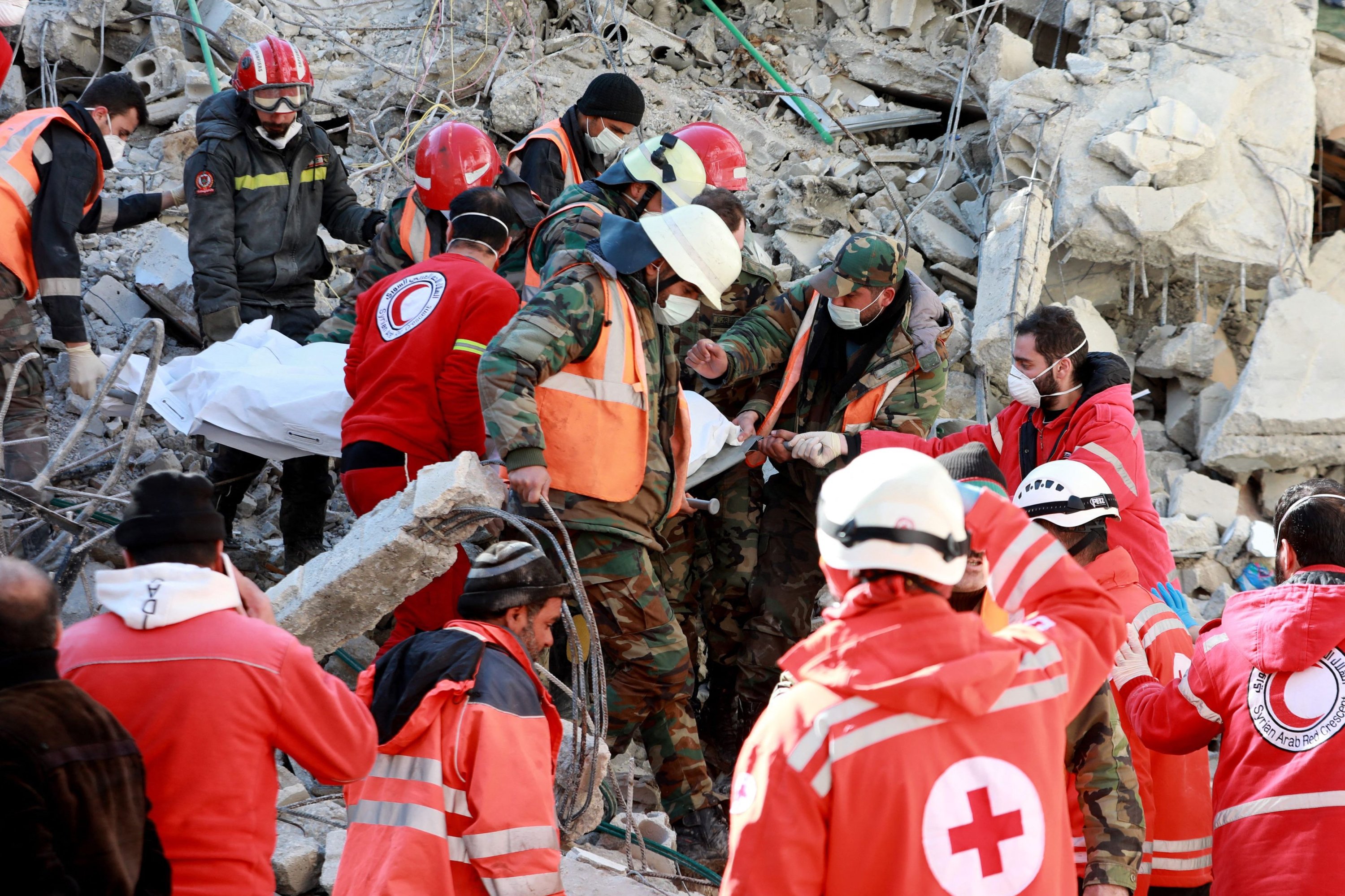 Anggota Palang Merah Lebanon membawa jenazah seorang korban dengan tandu yang diambil dari puing-puing bangunan yang runtuh, Damaskus, Suriah, 9 Februari 2023. (Foto AFP)