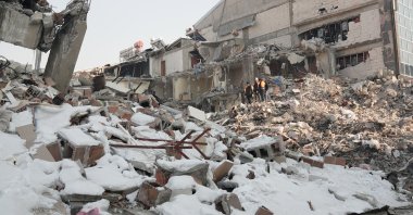 People walk among rubble, in the aftermath of the deadly earthquake, in the town of Elbistan, Kahramanmaras, Türkiye, Feb. 12, 2023. (Reuters Photo)