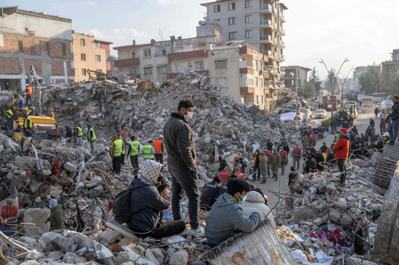 People stand on top of the rubble from collapsed buildings during rescue operations, in Hatay, Türkiye, Feb. 12, 2023. (AFP Photo)
