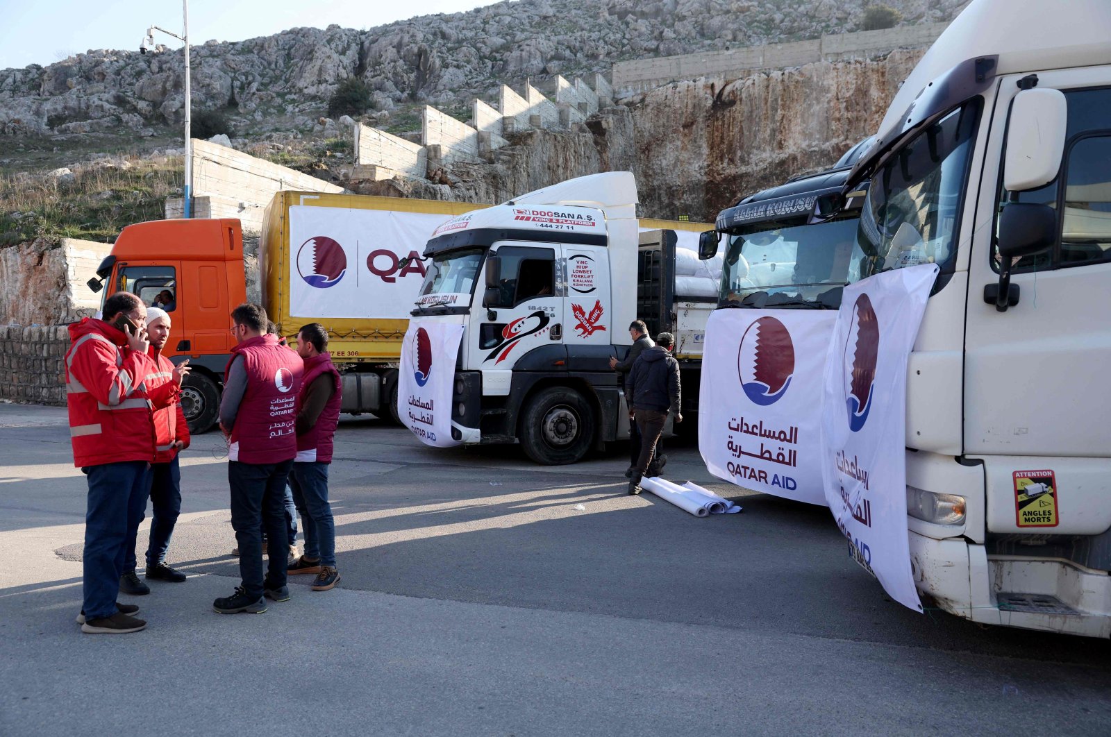 Men stand next to trucks, part of a convoy carrying aid provided by Qatar, in the aftermath of an earthquake, at Syria&#039;s Bab al-Hawa border crossing with Türkiye in the opposition-held northwestern province of Idlib, on Feb.13, 2023. (AFP Photo)