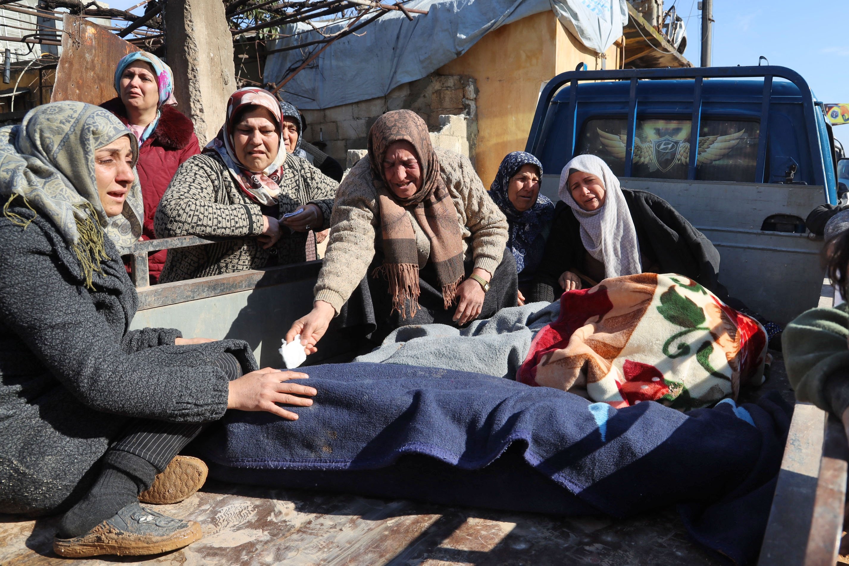 Wanita Suriah menangis di samping mayat yang tergeletak di belakang truk, Jandaris, Suriah, 7 Februari 2023. (Foto AFP)