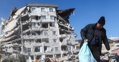 A man tries to salvage some belongings from the rubble at the site of collapsed buildings following a powerful earthquake, in the Nurdağı district of Gaziantep, southeastern Türkiye, Feb. 13, 2023. (EPA Photo)
