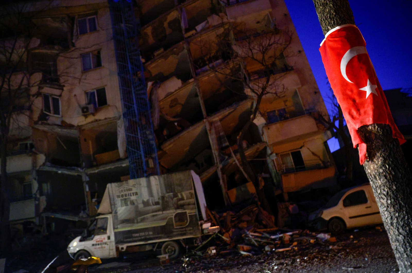 A Turkish flag is seen on a pole in front of a collapsed building, as rescues continue in the aftermath of a deadly earthquake in Kahramanmaraş, Türkiye, Feb. 12, 2023. (Reuters Photo)