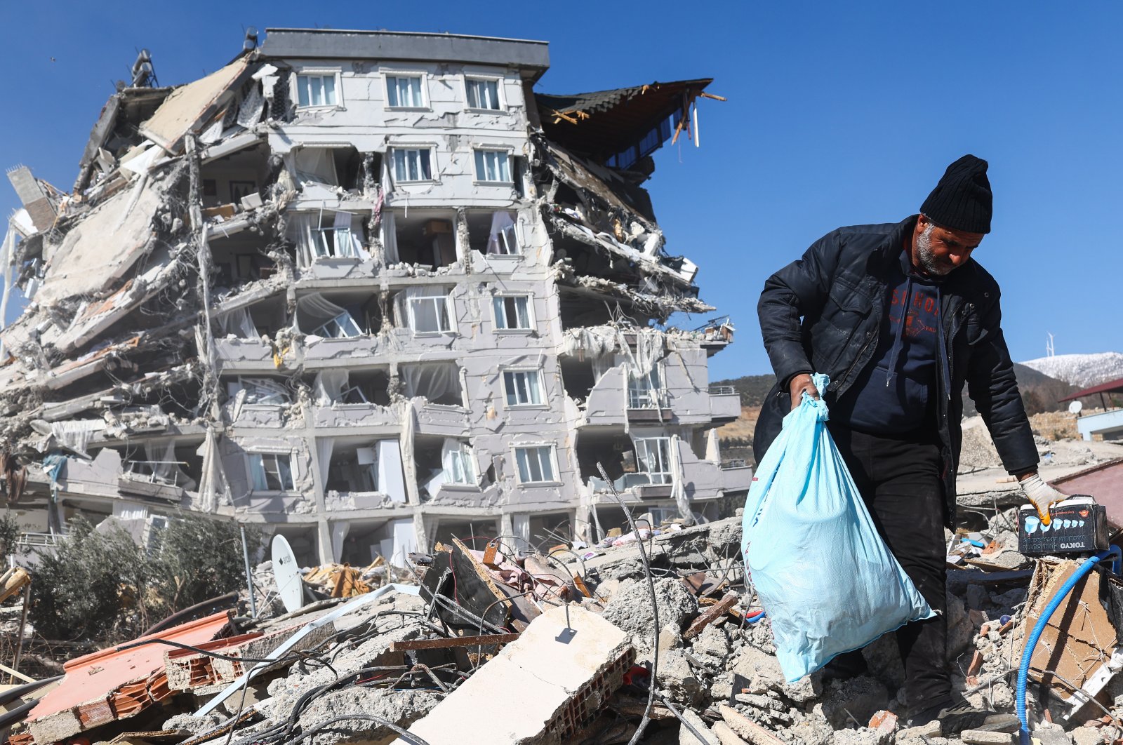 A man tries to salvage some belongings from the rubble at the site of collapsed buildings following a powerful earthquake, in the Nurdağı district of Gaziantep, southeastern Türkiye, Feb. 13, 2023. (EPA Photo)