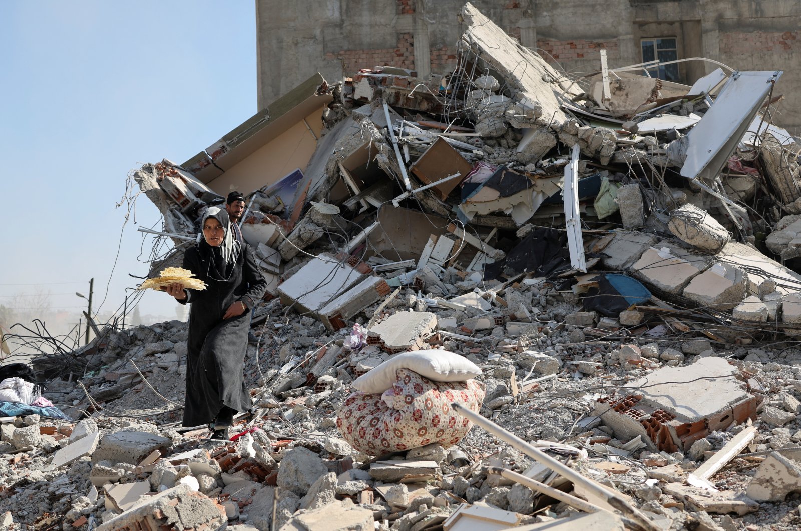 A woman carries bread taken out of the rubble of her house, in Kahramanmaraş, southeastern Türkiye, Feb. 14, 2023. (Reuters Photo)