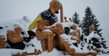 A memorial statue with the Ukrainian flag tied across the shoulders of one of the statues is covered by snow in Chasiv Yar, Ukraine, Feb. 14, 2023. (AFP Photo)