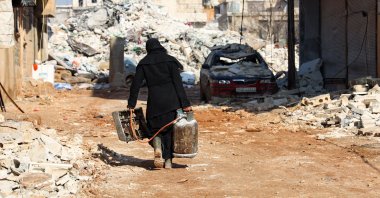 A woman salvages a small stove and a gas canister, as search and rescue operations continue days after a deadly earthquake hit Türkiye and Syria, in the opposition-held town of Jindayris, held part of Syria&#039;s Aleppo province, Feb. 10, 2023. (AFP Photo)