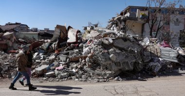 People walk past a collapsed building in the aftermath of the devastating earthquake in Nurdağı, Gaziantep, southeastern Türkiye, Feb. 13, 2023. (EPA Photo)