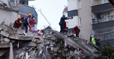 People and rescue workers stand on the rubble of a collapsed building following the deadly earthquake in Adana, Türkiye, Feb. 7, 2023. (Reuters Photo)