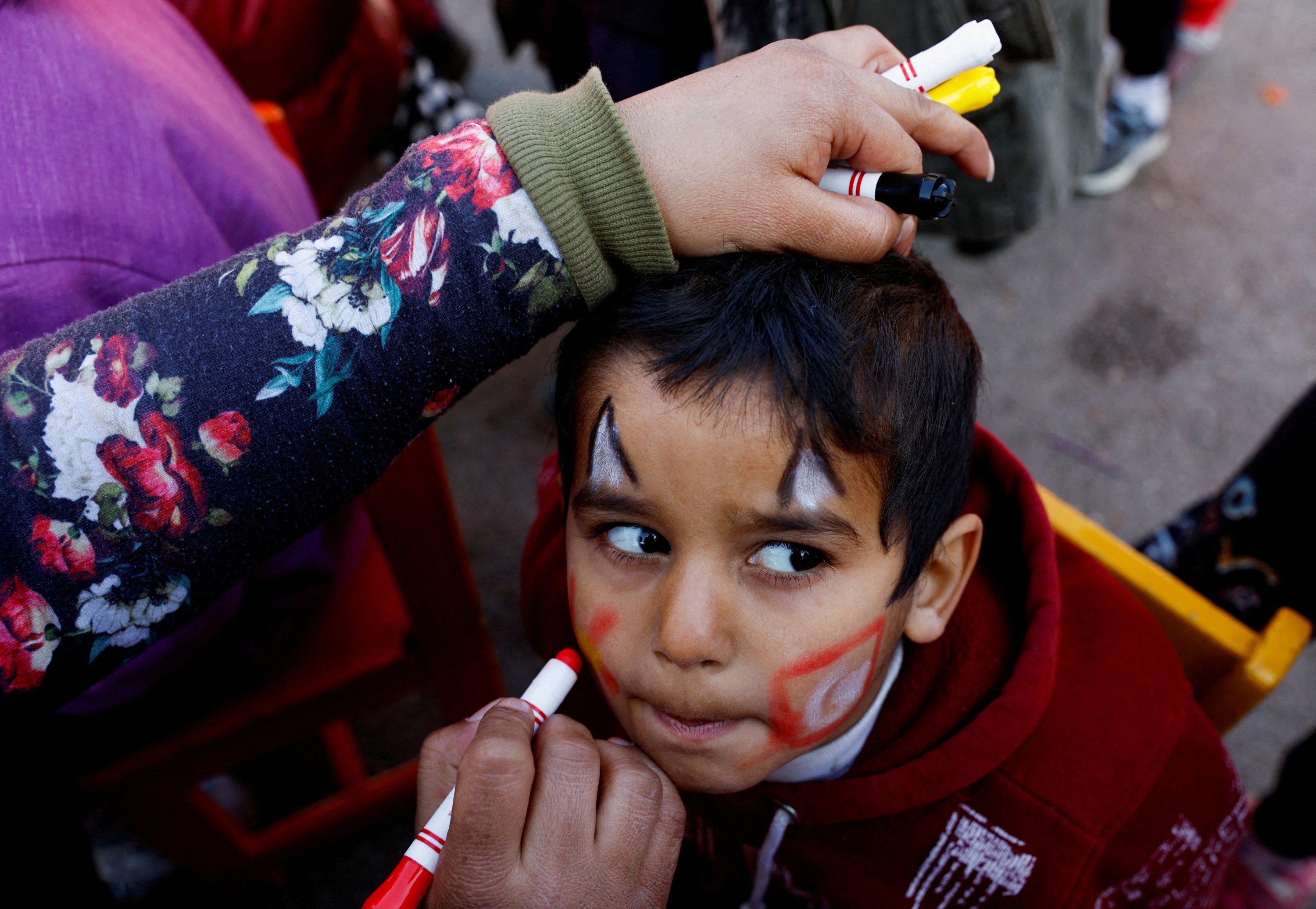 Seorang wanita melukis wajah seorang anak dalam kegiatan untuk menghibur dan mendukung kesehatan mental anak-anak yang terkena dampak gempa mematikan di Osmaniye, Türkiye tenggara, 16 Februari 2023. (Foto Reuters)