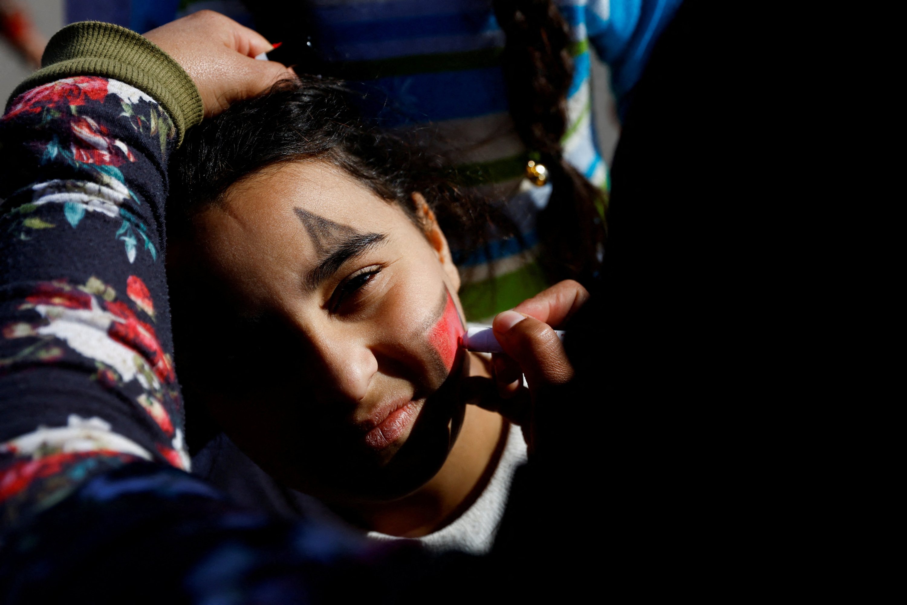 Seorang wanita melukis wajah seorang anak dalam kegiatan untuk menghibur dan mendukung kesehatan mental anak-anak yang terkena dampak gempa mematikan di Osmaniye, Türkiye tenggara, 16 Februari 2023. (Foto Reuters)