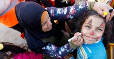 A woman paints a child&#039;s face as part of entertainment for children affected by the deadly earthquake in Osmaniye, southeastern Türkiye, Feb. 16, 2023. (Reuters Photo)