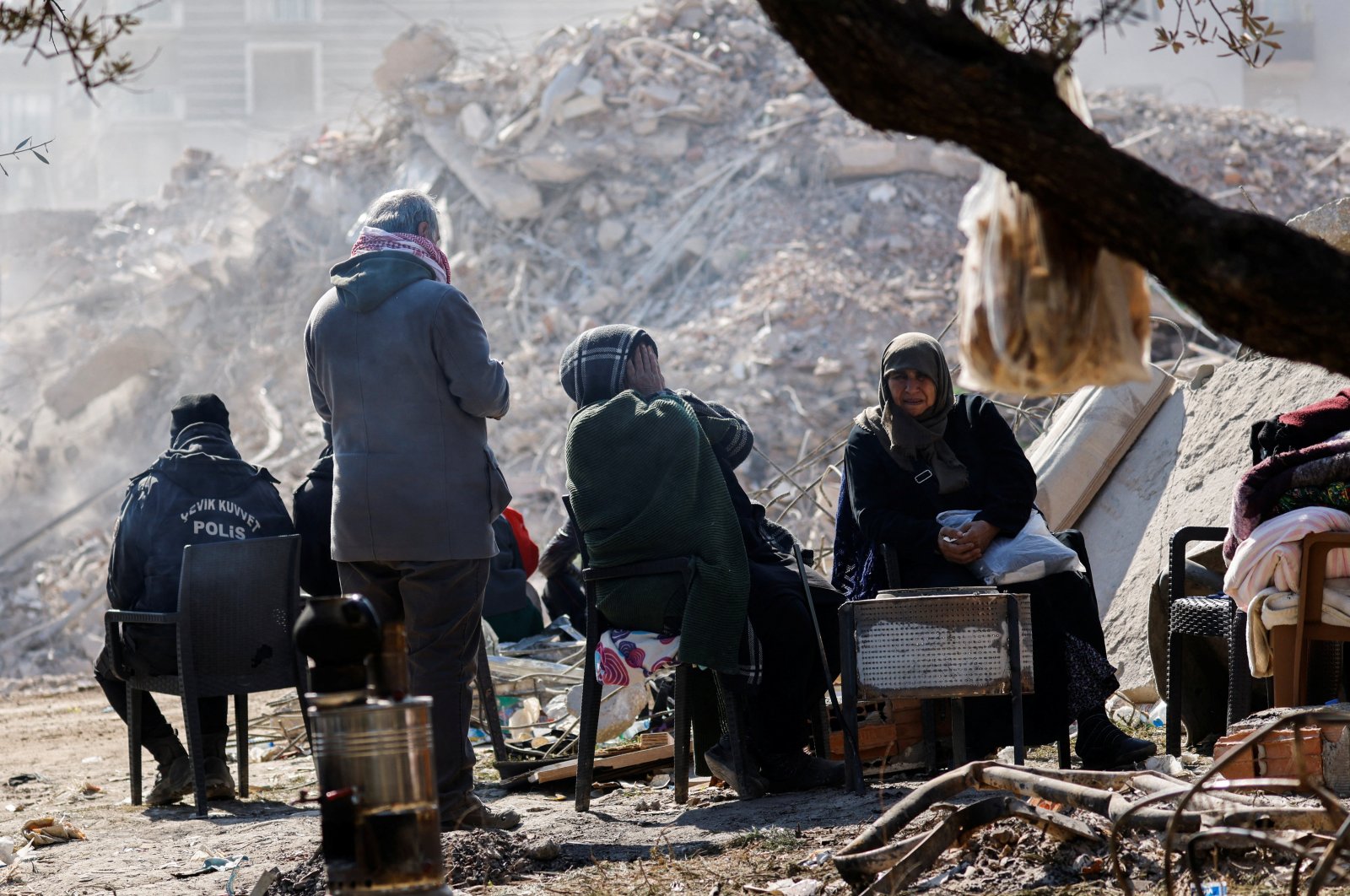 People sit at a camp next to the site of a destroyed high-end building, in the aftermath of the earthquake in Antakya, Hatay, southern Türkiye, Feb. 16, 2023. (Reuters Photo)