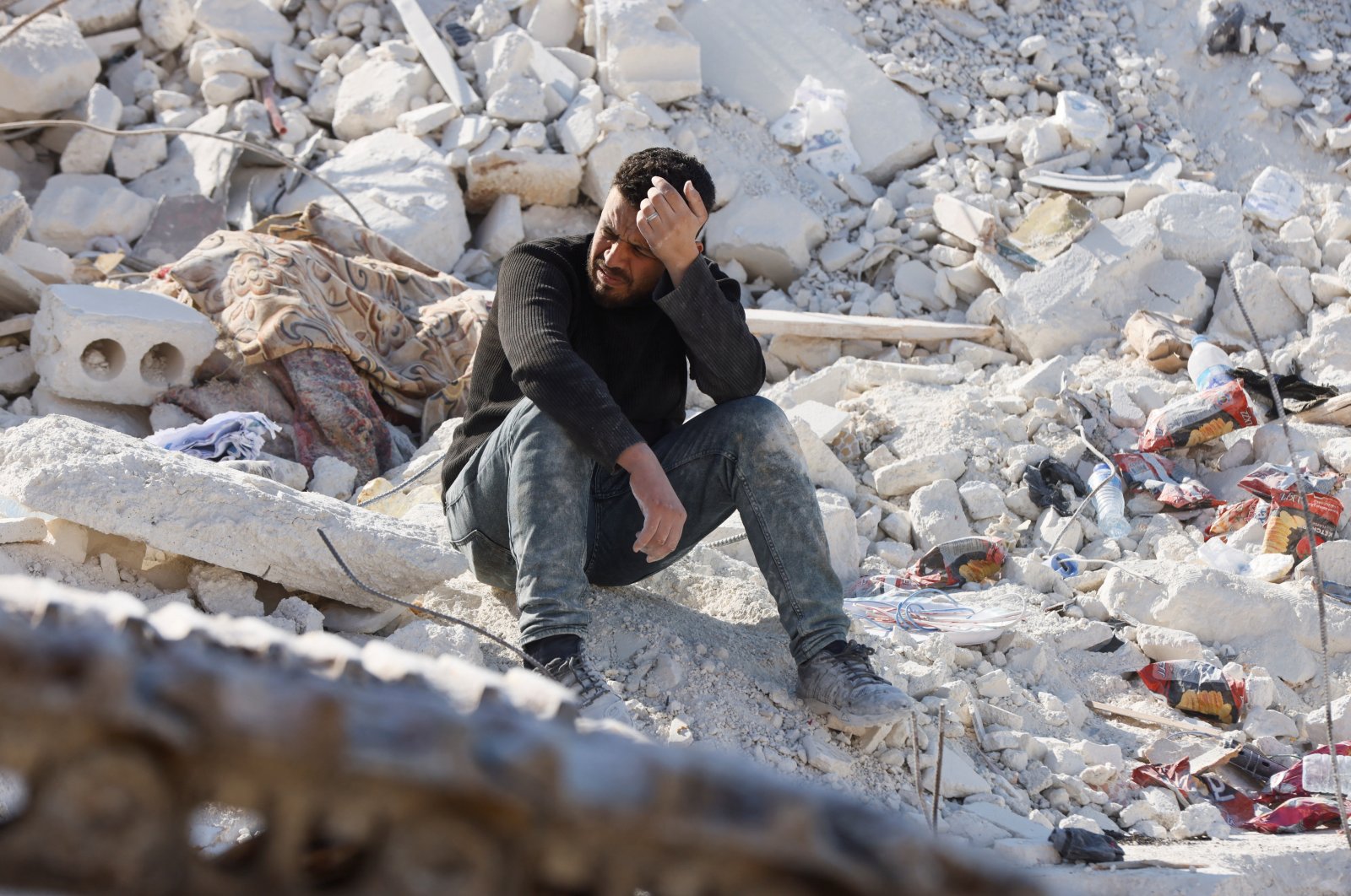 A man sits atop the ruins of a home after a deadly earthquake in the opposition-held town of Harem, Idlib, Syria, Feb. 14, 2023. (Reuters Photo)