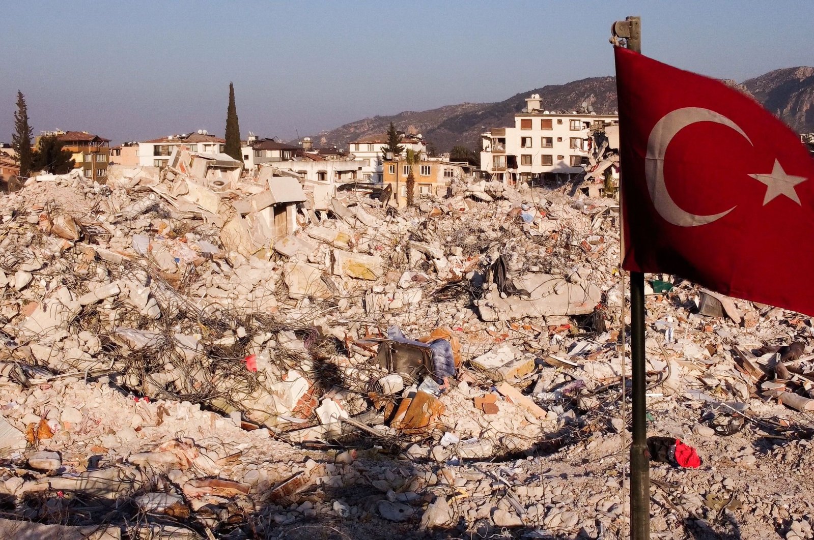 This aerial photograph shows a Turkish flag waving over the rubble of destroyed buildings in Antakya, a week after a deadly earthquake struck parts of Türkiye and Syria, Hatay, Türkiye, Feb. 14, 2023. (AFP Photo)