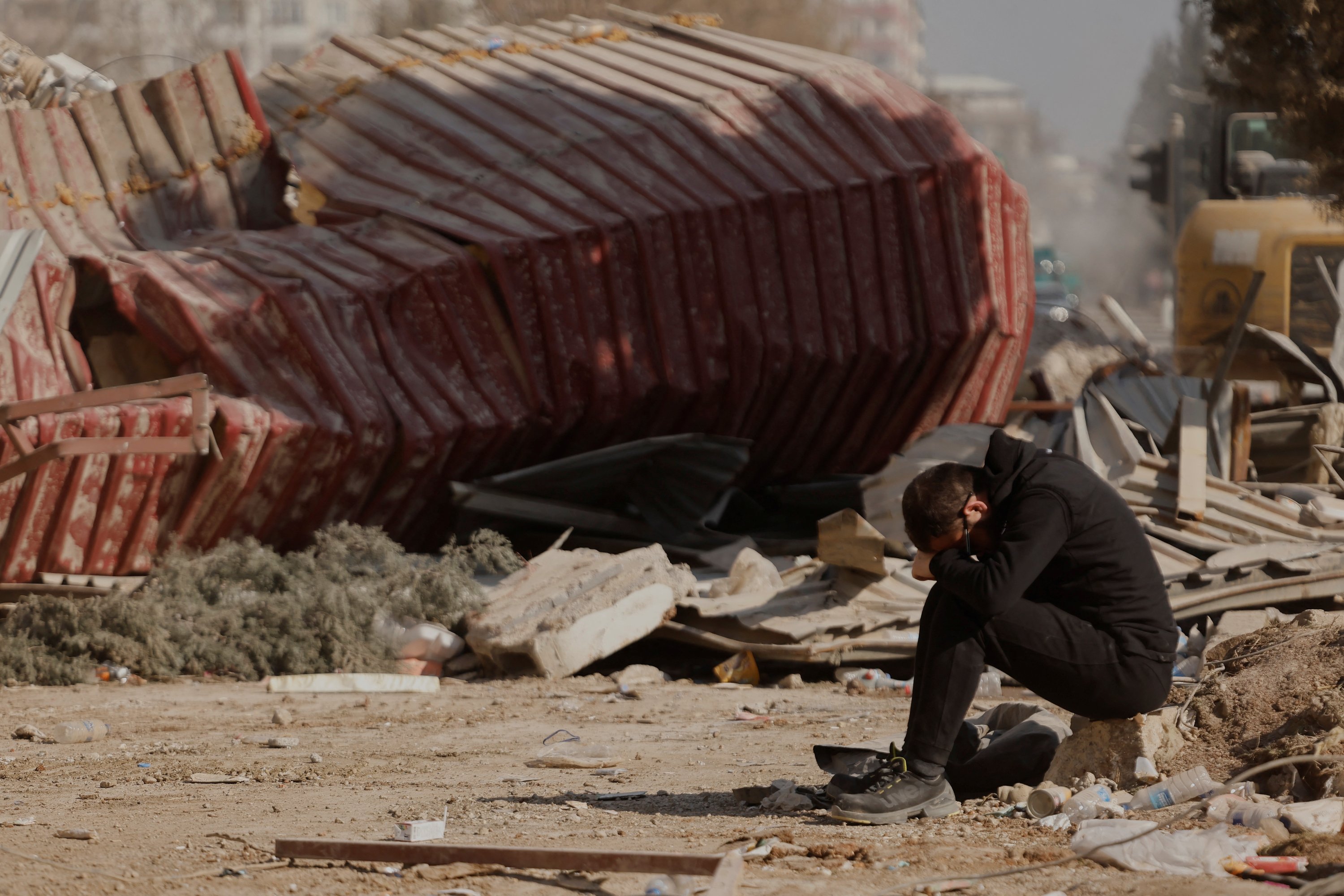 Seorang pria bereaksi ketika orang-orang mencari barang-barang pribadi di puing-puing blok apartemen yang runtuh, setelah gempa mematikan, Kahramanmaraş, Türkiye, 18 Februari 2023. (Foto Reuters)