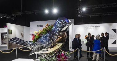 Visitors chat next to an artwork by U.S. artist Jeff Koons, on display at the international art show artgeneve, in Geneva, Switzerland, Jan. 25, 2023. (EPA Photo)