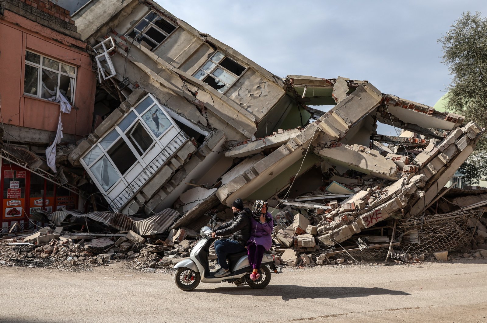People ride a scooter in front of a collapsed building after the powerful earthquake in Adıyaman, Türkiye, Feb. 19, 2023. (EPA Photo)