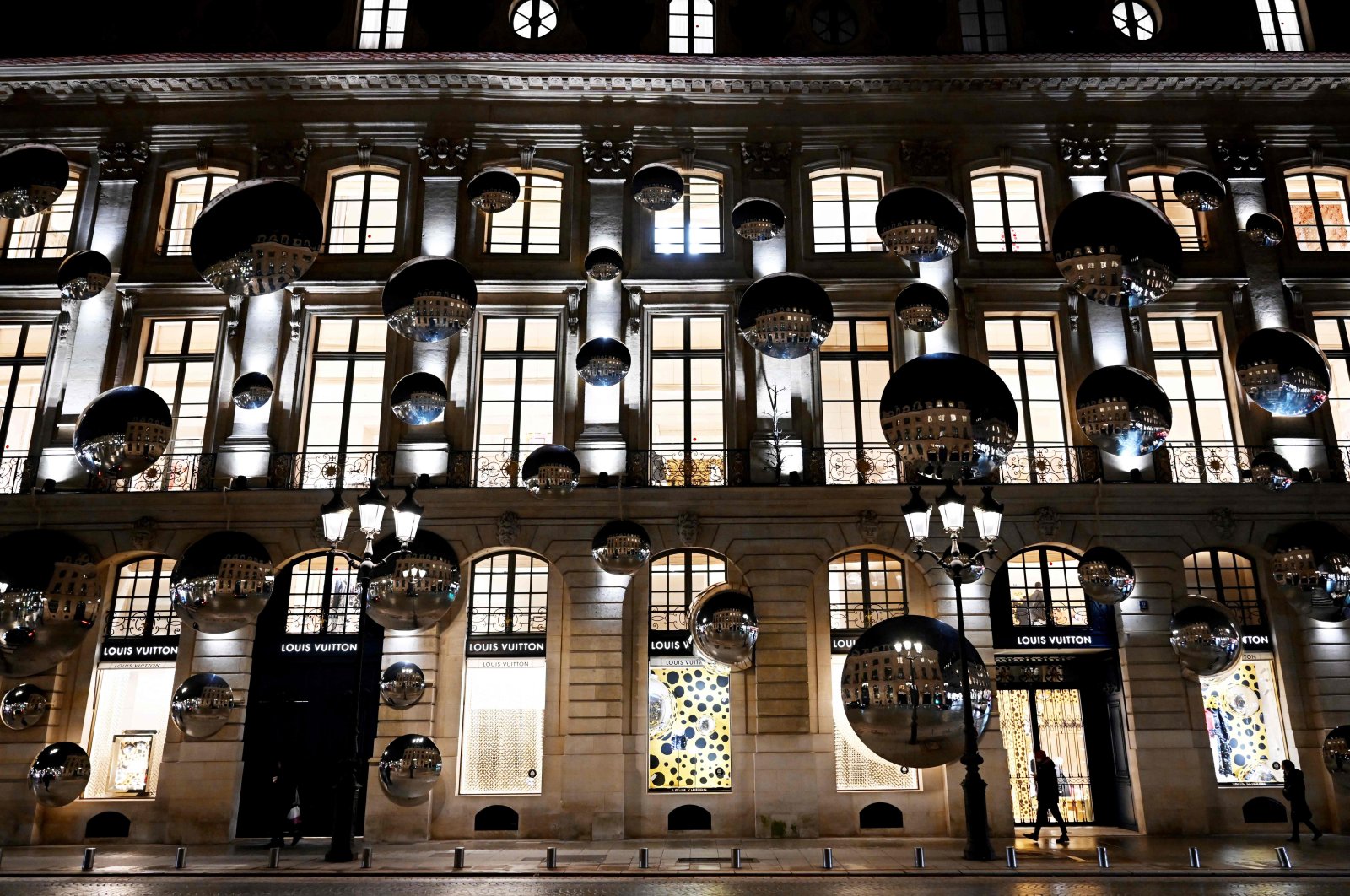 A pedestrian walks past a display of convex mirrors adorning the exterior of the Louis Vuitton flagship building off Place Vendome in Paris, France, Jan. 26, 2023. (AFP Photo)