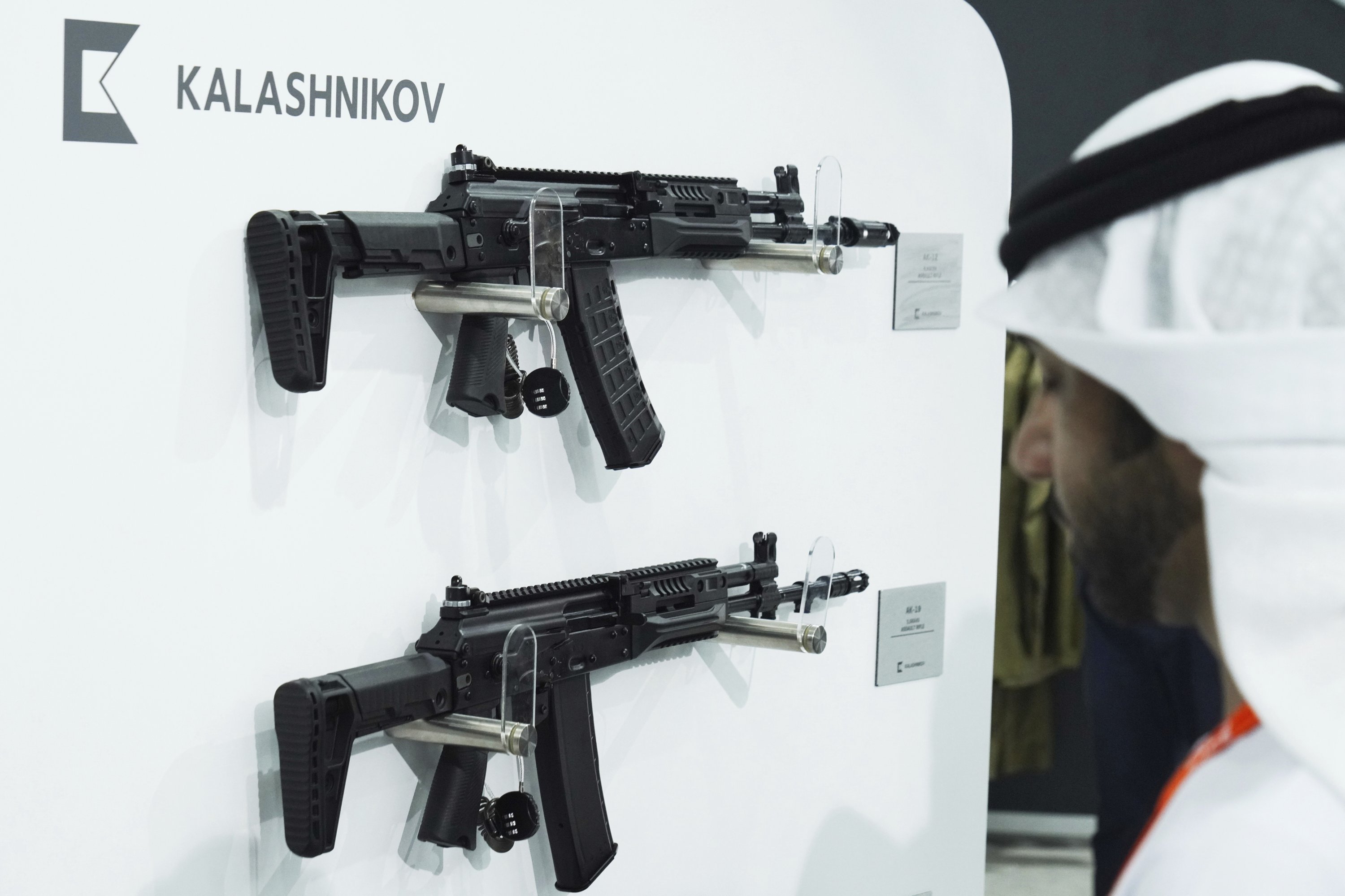 Seorang pria Emirat berjalan melewati senapan Kalashnikov di sebuah tenda produsen senjata Rusia di Pameran dan Konferensi Pertahanan Internasional di Abu Dhabi, Uni Emirat Arab, Senin, 20 Februari 2023. (Foto AP)