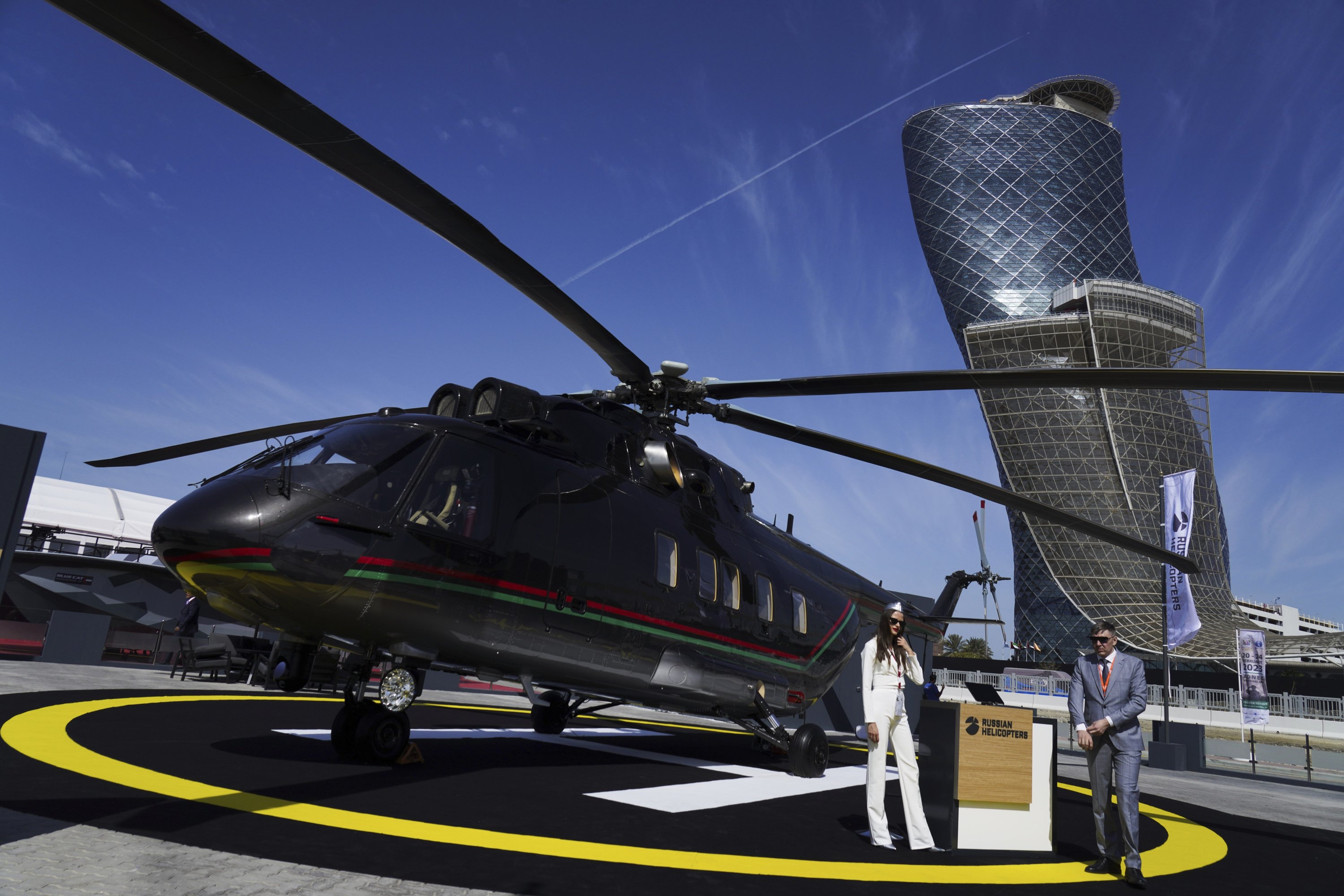 Penjual Rusia berdiri di dekat helikopter buatan Russian Helicopters di Pameran dan Konferensi Pertahanan Internasional di Abu Dhabi, Uni Emirat Arab, Senin, 20 Februari 2023. (Foto AP)