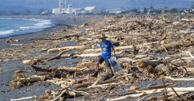 A resident walks among the debris washed ashore from Cyclone Gabrielle, Napier, New Zealand, Feb. 19, 2023. (AP Photos)