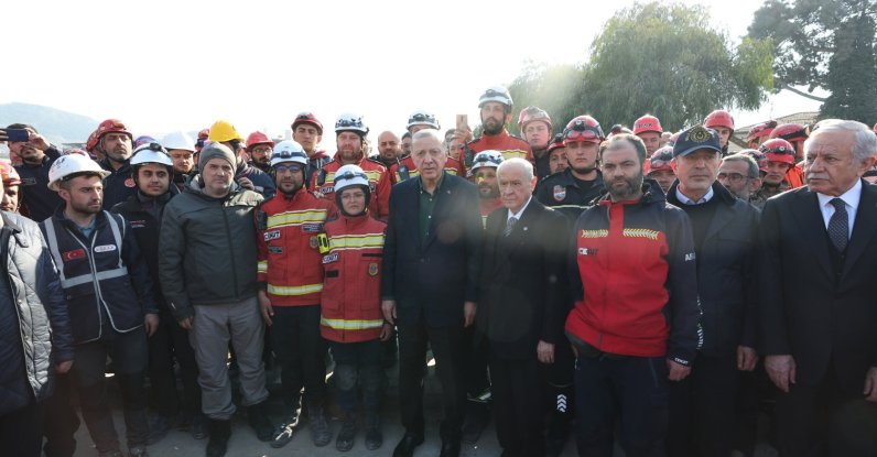 President Recep Tayyip Erdoğan (C) and Nationalist Movement Party (MHP) leader Devlet Bahçeli (R) pose for a photo with a search and rescue crew, in Hatay, southern Türkiye, Feb. 20, 2023. (AA Photo)