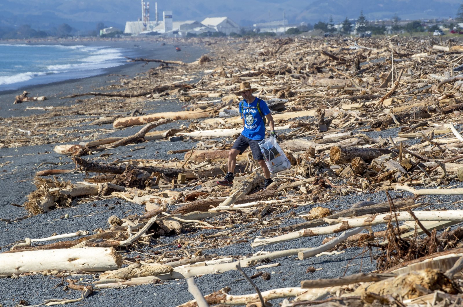 A resident walks among the debris washed ashore from Cyclone Gabrielle, Napier, New Zealand, Feb. 19, 2023. (AP Photos)
