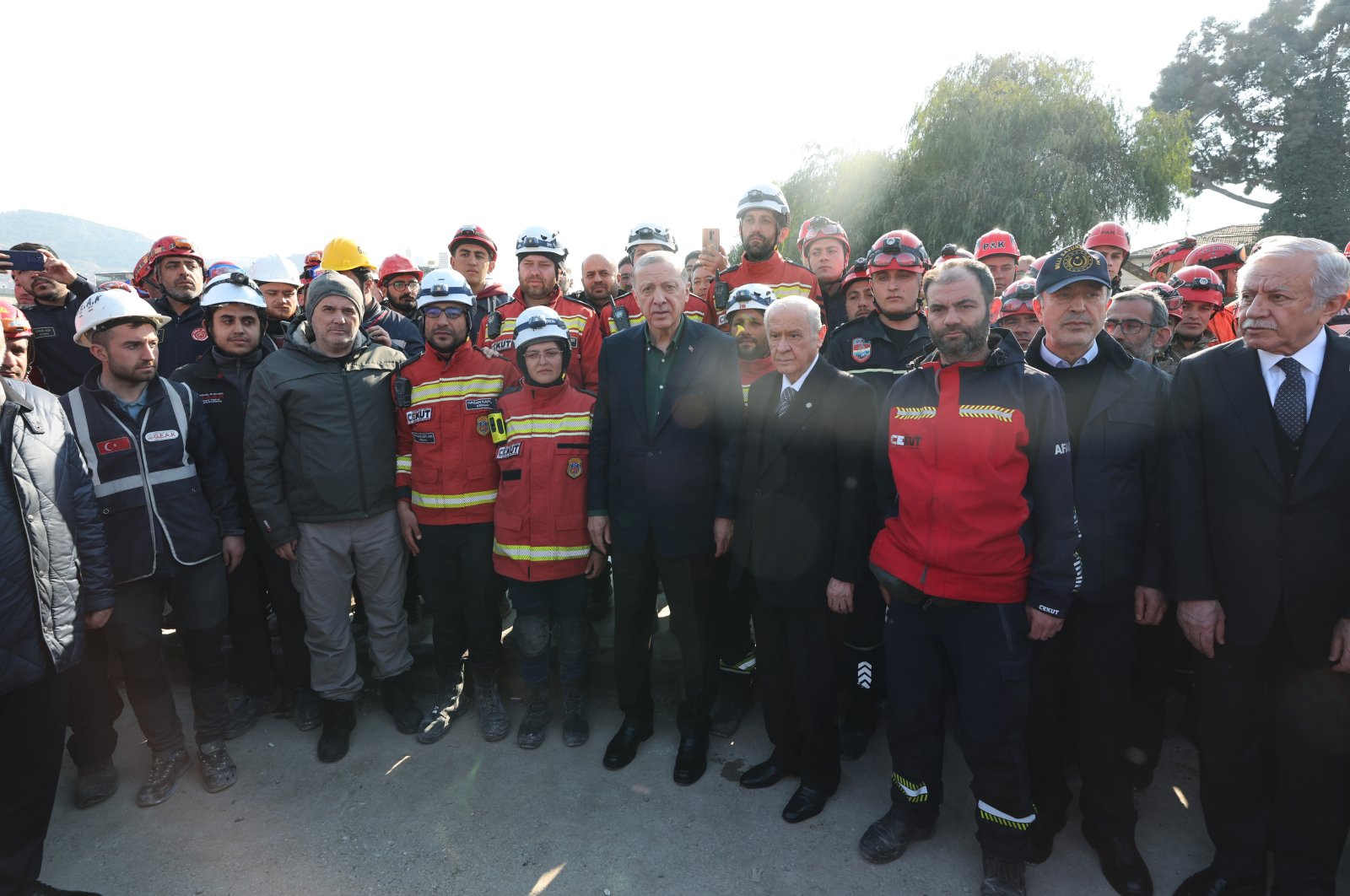 President Recep Tayyip Erdoğan (C) and Nationalist Movement Party (MHP) leader Devlet Bahçeli (R) pose for a photo with a search and rescue crew, in Hatay, southern Türkiye, Feb. 20, 2023. (AA Photo)