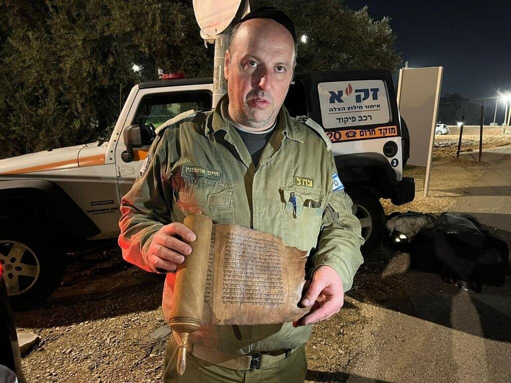 The photo published by the Israeli rescue team ZAKA shows one of the volunteers holding the Book of Esther. (@Ynetnews / Twitter)