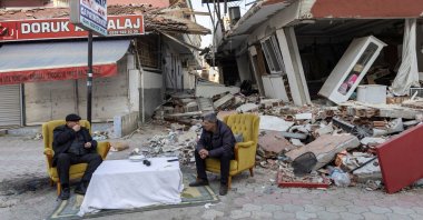 Men sit and talk in front of destroyed properties in the aftermath of the deadly earthquake in Antakya, Hatay province, Türkiye, Feb. 20, 2023. (Reuters Photo)
