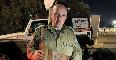 The photo published by the Israeli rescue team ZAKA shows one of the volunteers holding the Book of Esther. (@Ynetnews / Twitter)