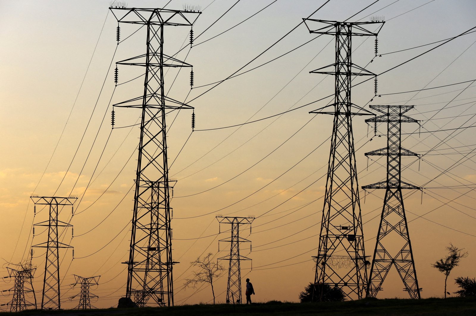 A man walks beneath electricity pylons during frequent power outages from South African utility Eskom, caused by its aging coal-fired plants, in Orlando, Soweto, South Africa, Jan. 16, 2023. (Reuters Photo)