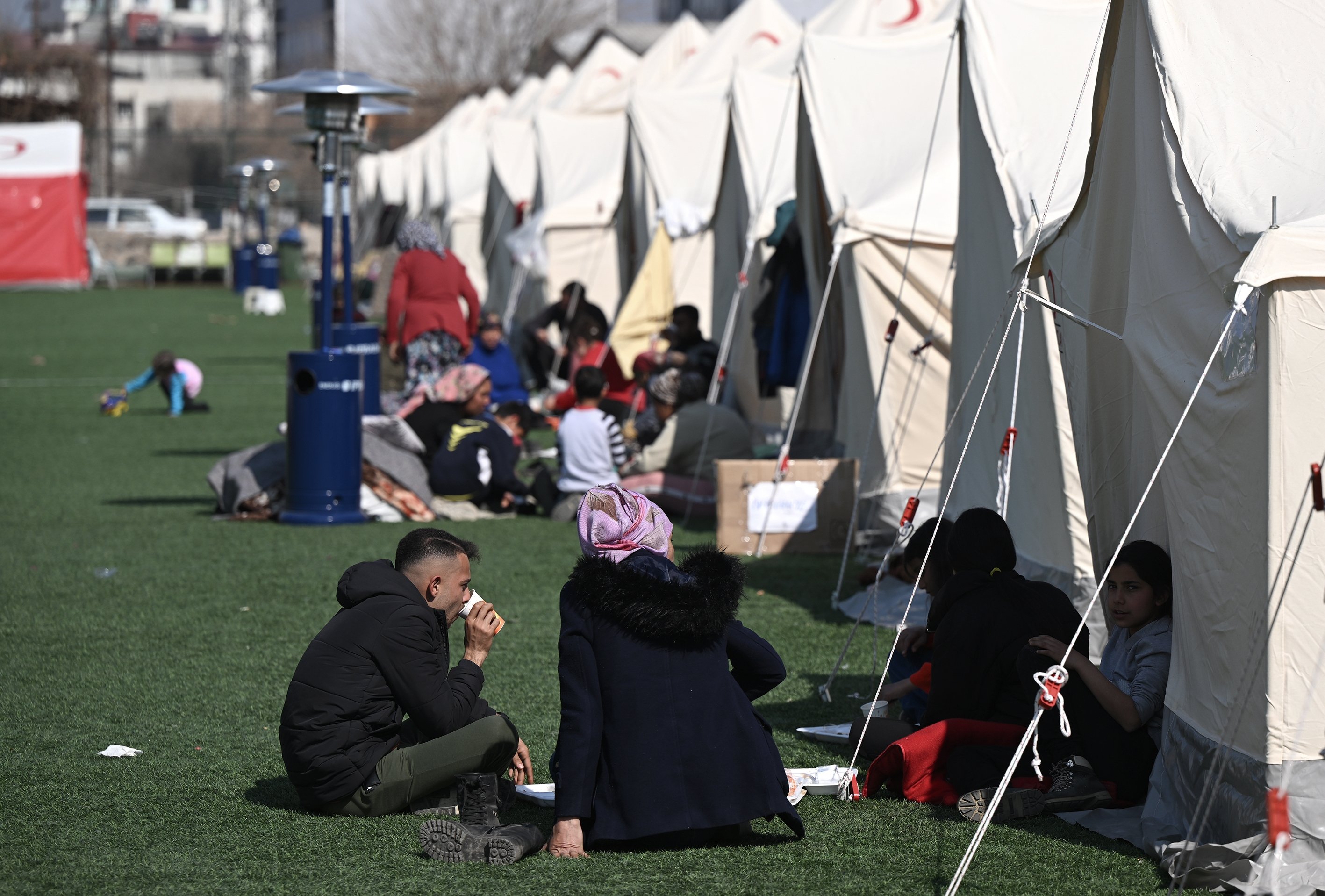 Para penyintas gempa duduk di dekat tenda yang didirikan di Stadion Kota Kırıkhan di Hatay, tenggara Türkiye, 22 Februari 2023. (Foto AA)