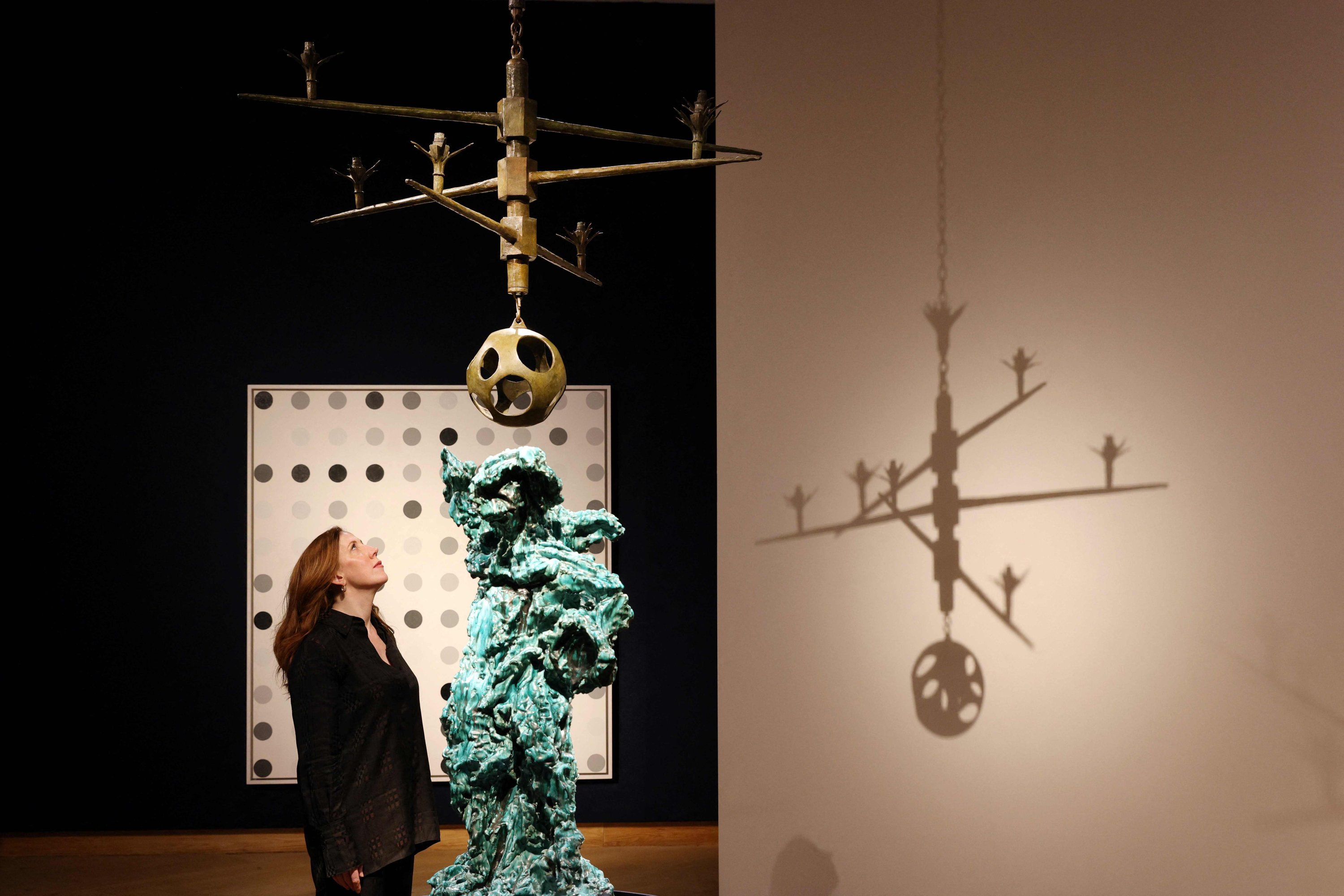 Michelle McMillan, salah satu kepala penjualan di Christie's mengagumi lampu gantung karya seniman Italia Alberto Giacometti di rumah lelang Christie selama pratinjau pers menjelang 