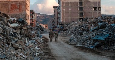 Turkish Armed Forces members walk among collapsed buildings, a day after a 6.4 magnitude earthquake struck the region, in the coastal city of Samandağ, Türkiye, Feb. 21, 2023. (AFP Photo)