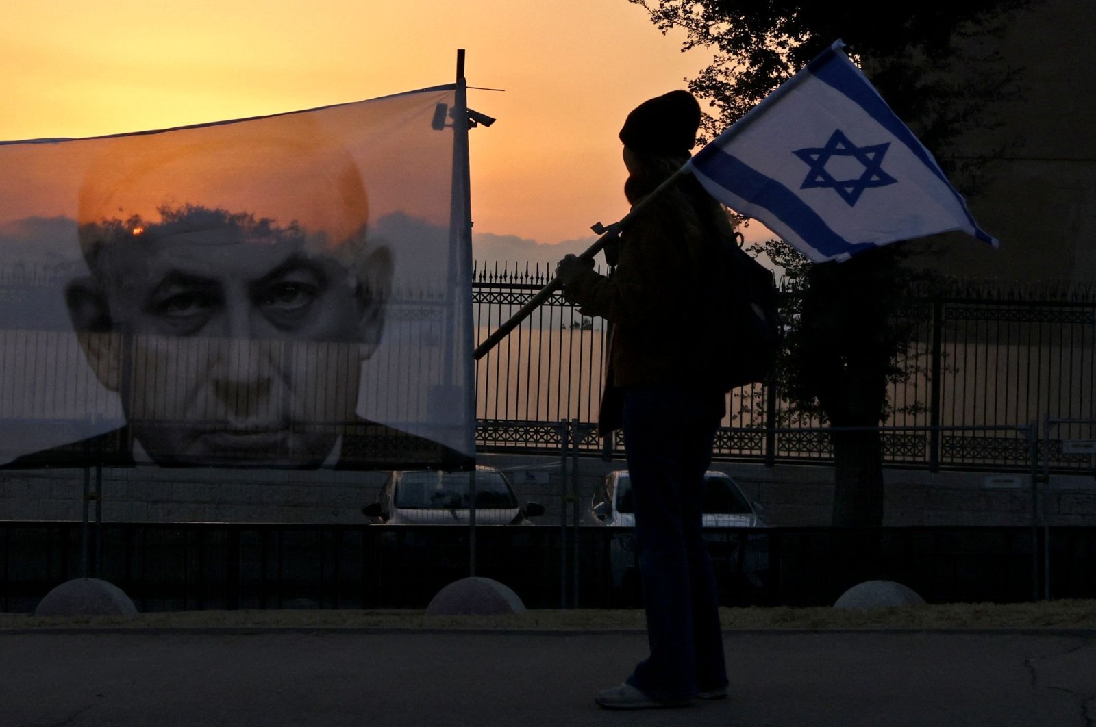 A protester walks past a banner depicting Israeli Prime Minister Benjamin Netanyahu, Jerusalem, Israel, Feb. 20, 2023. (AFP Photo)
