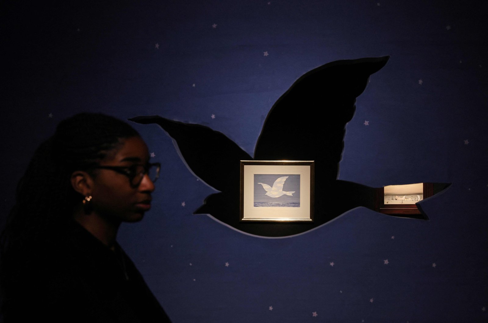 A gallery employee looks on alongside "Souvenir de voyage" painting by Belgian artist Rene Magritte at Christie&#039;s auction house during the press preview ahead of "The Art of the Surreal evening sale"  London, U.K., Feb. 21, 2023. (AFP Photo)
