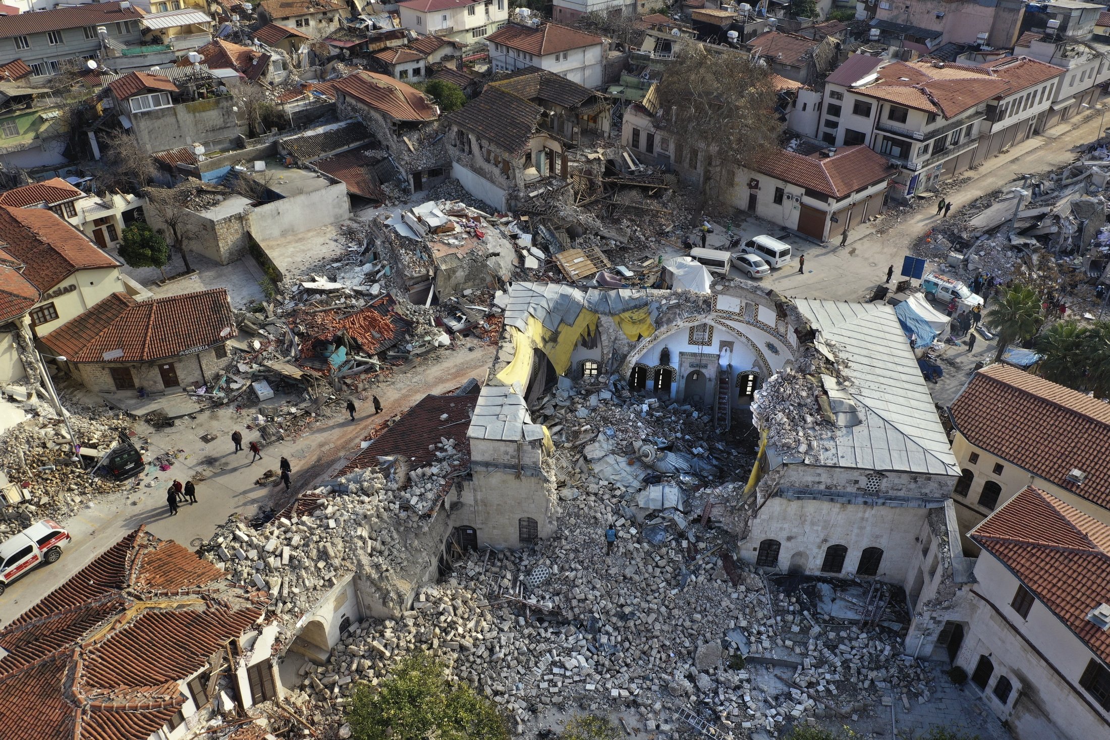 Türk vatandaşları, 11 Şubat 2023, Antakya'nın eski kentinde, büyük depremde yıkılan tarihi Habib Najjar camisinin yanından geçiyor. (AP Fotoğrafı)