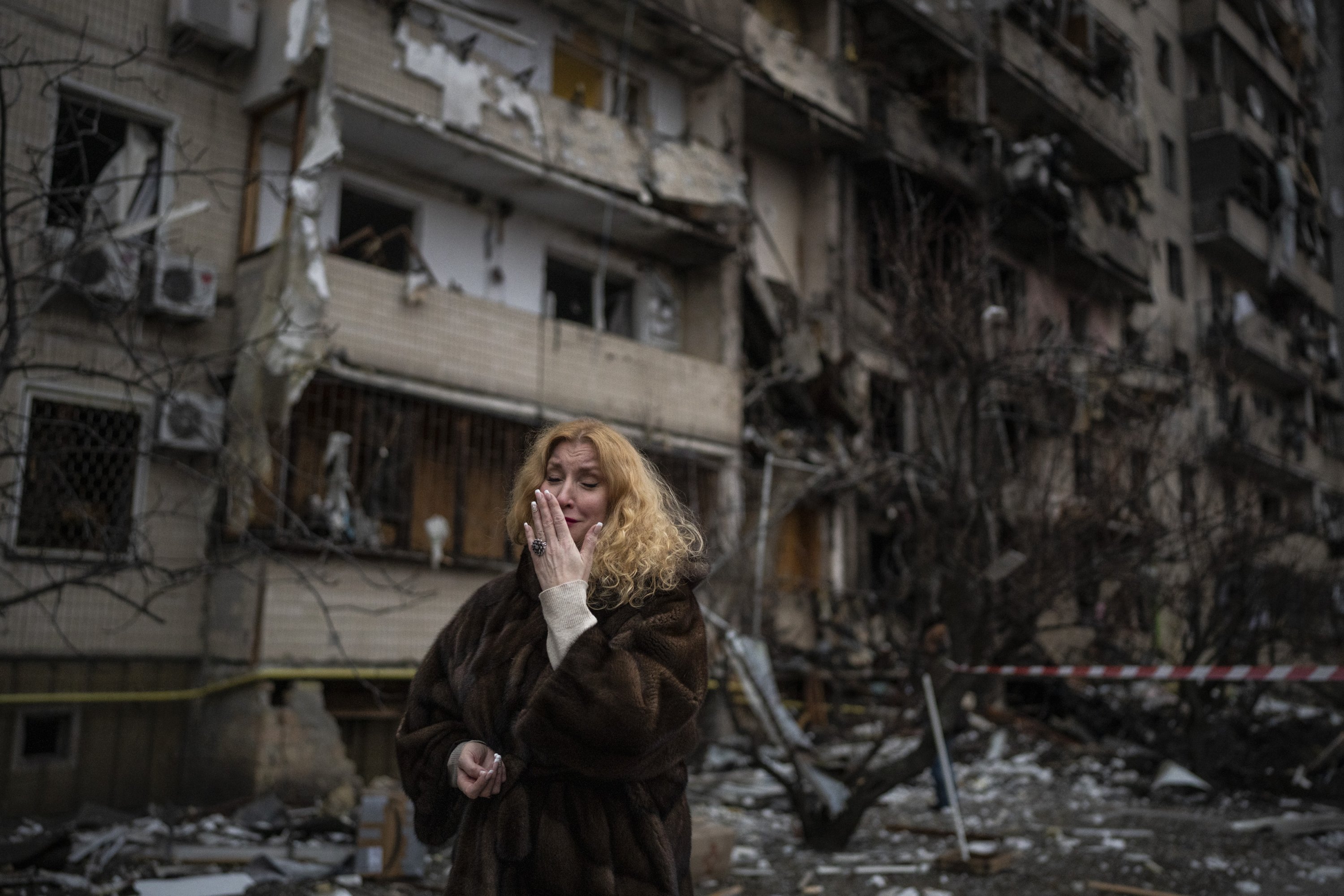 Natali Sevriukova diliputi emosi saat dia berdiri di luar gedung apartemennya yang hancur setelah serangan roket di Kyiv, Ukraina, 25 Februari 2022. (Foto AP)