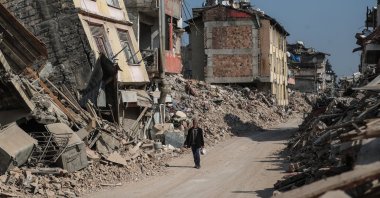 A man walks past collapsed buildings in the aftermath of powerful earthquakes in Hatay, southern Türkiye, Feb. 23 2023. (EPA Photo)