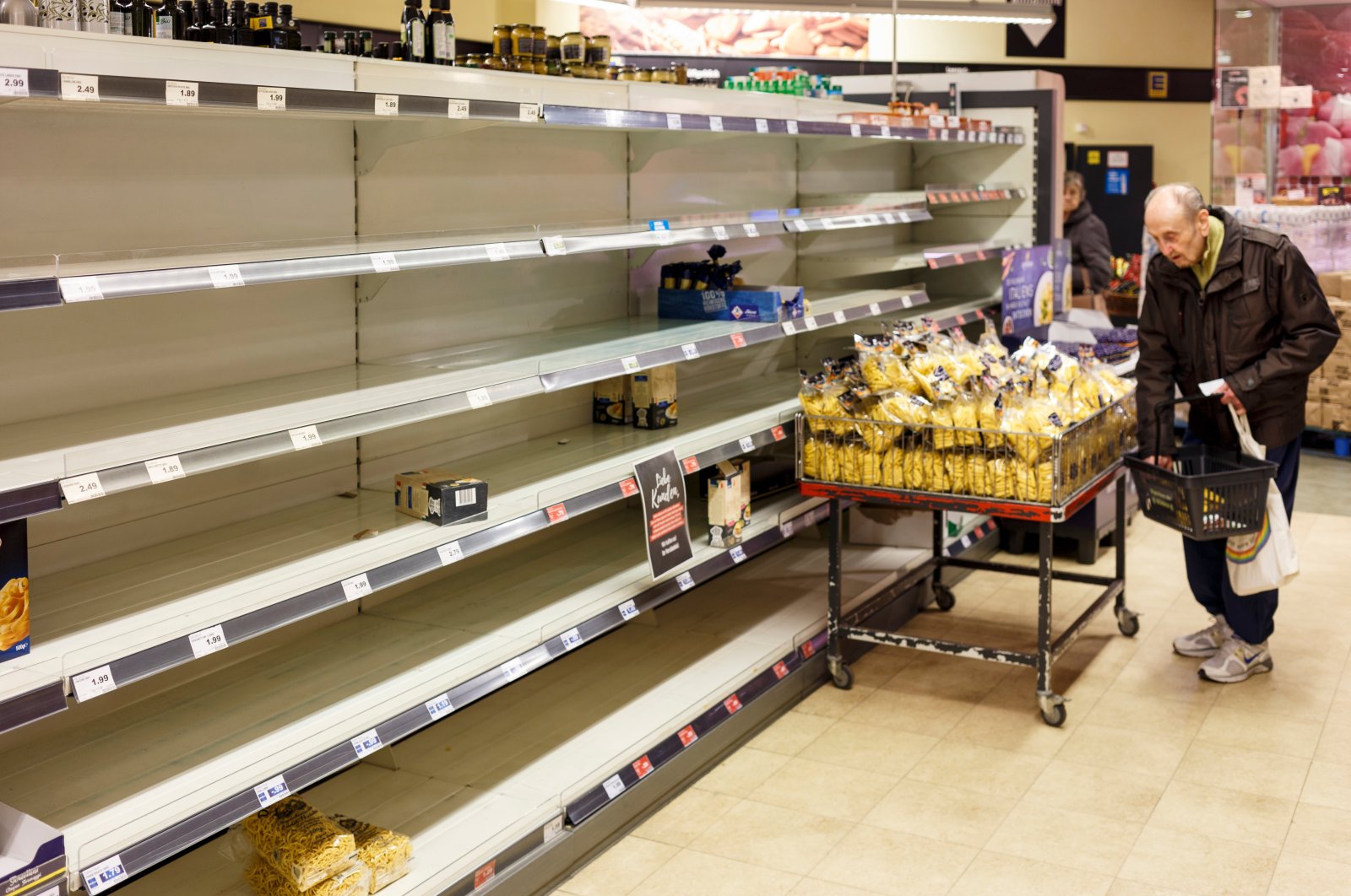 A senior citizen next to empty supermarket shelves cleared due to panic buying because of widespread fear early in the COVID-19 pandemic, Berlin, Germany, March 18, 2020. (Shutterstock File Photo)