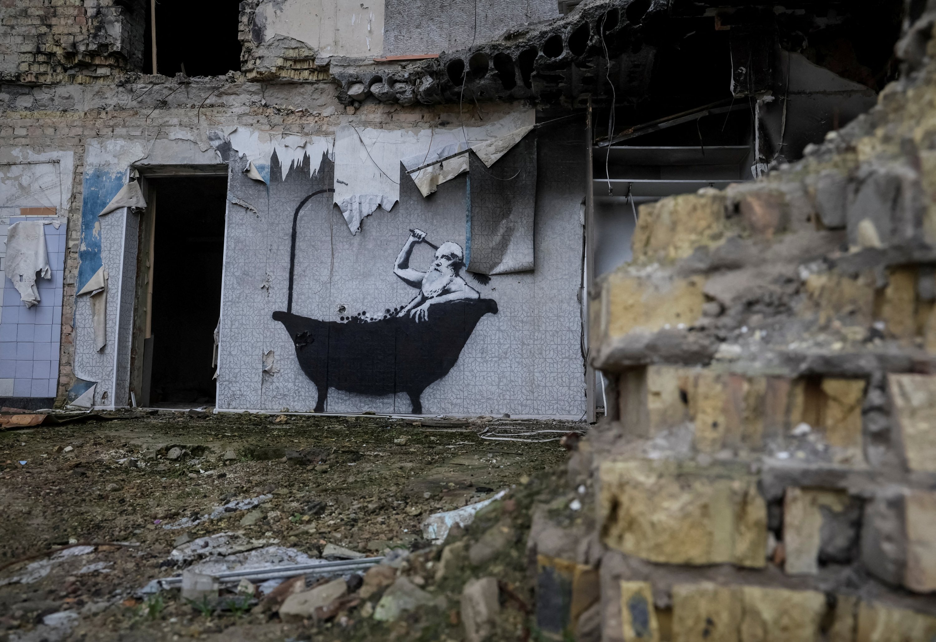 Grafiti baru dengan gaya khas Banksy terlihat di dinding bangunan yang hancur di desa Horenka, Ukraina, pada 13 November 2022. (Foto Reuters)