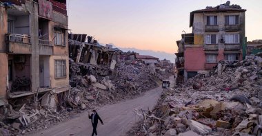A man walks past collapsed buildings in Antakya, Türkiye, Feb. 20, 2023. (AFP Photo)