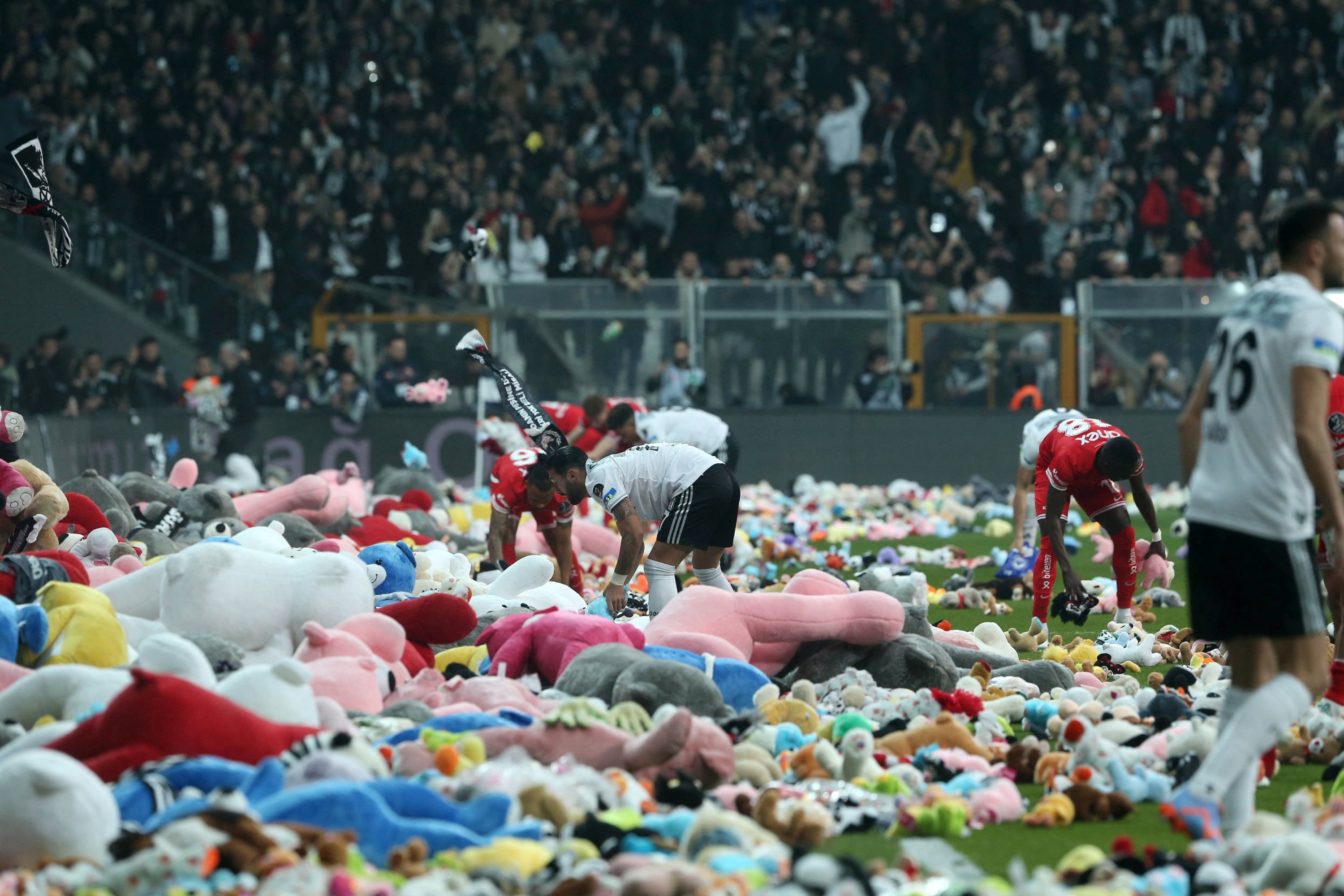Para pemain mengumpulkan mainan dan boneka beruang dari lapangan saat para penggemar Beşiktaş melemparkannya selama pertandingan sepak bola Süper Lig Turki antara Beşiktaş dan Antalyaspor di stadion Vodafone, Istanbul, Türkiye, 26 Februari 2023. (Foto DHA)