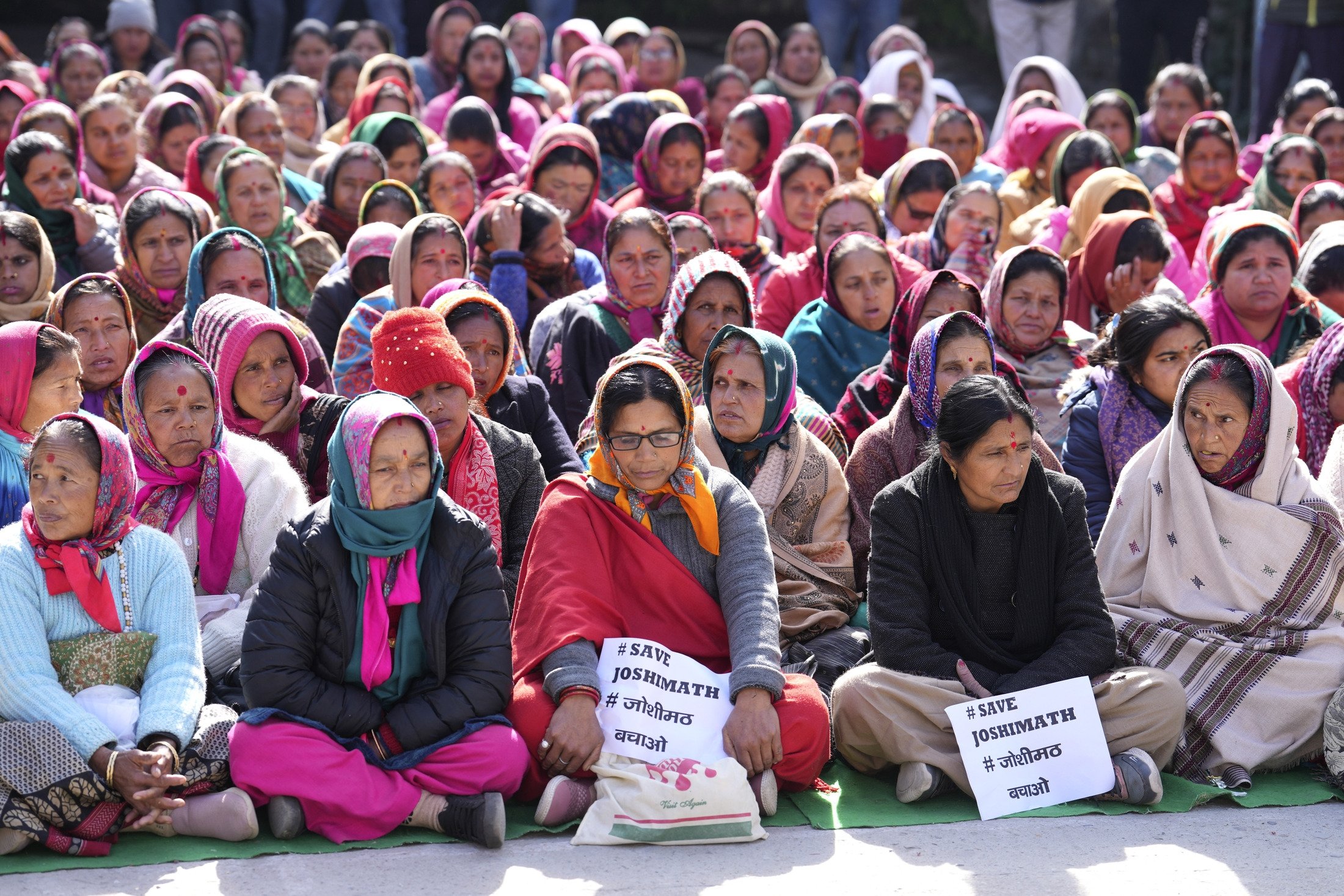 Kasabalarını kurtarmak isteyen bir grup kadın, 19 Ocak 2023, Hindistan'ın Uttarakhand eyaletindeki Himalaya dağ eyaletindeki Joshimath'ta bir oturma eylemine katılıyor. (AP Fotoğrafı)