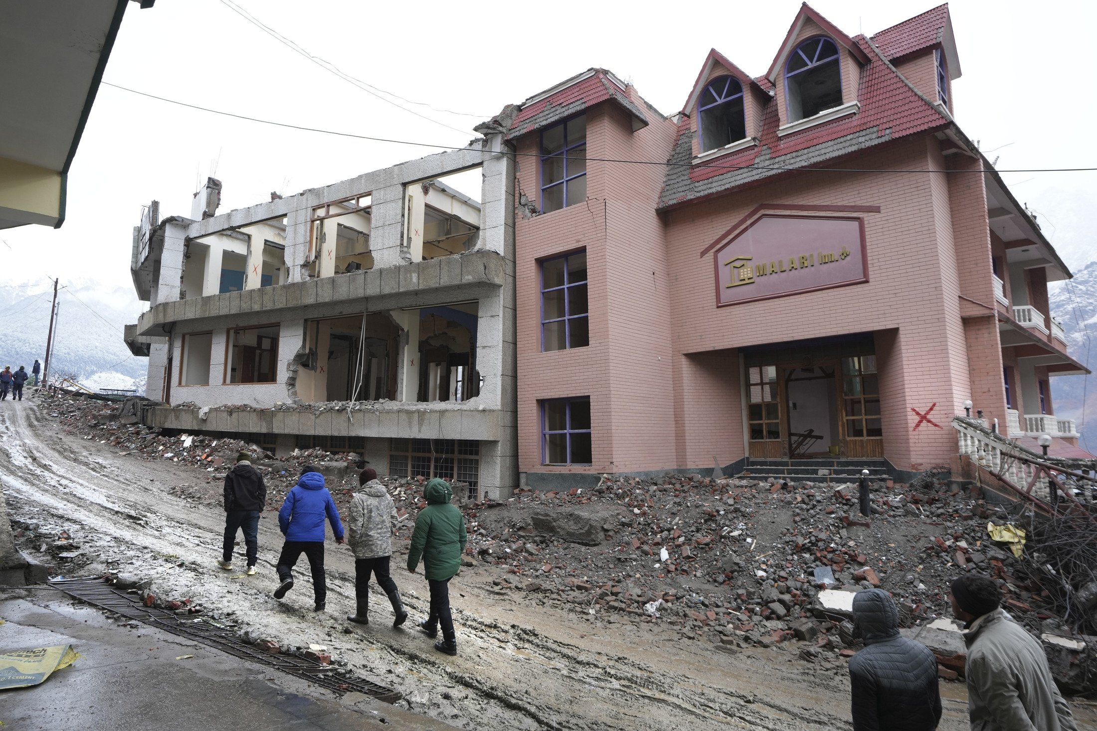 Sakinler, 20 Ocak 2023, Hindistan'ın Uttarakhand Himalaya dağ eyaletindeki Joshimath'ta yıkılmış bir otelin önünden geçiyor. (AP Fotoğrafı)